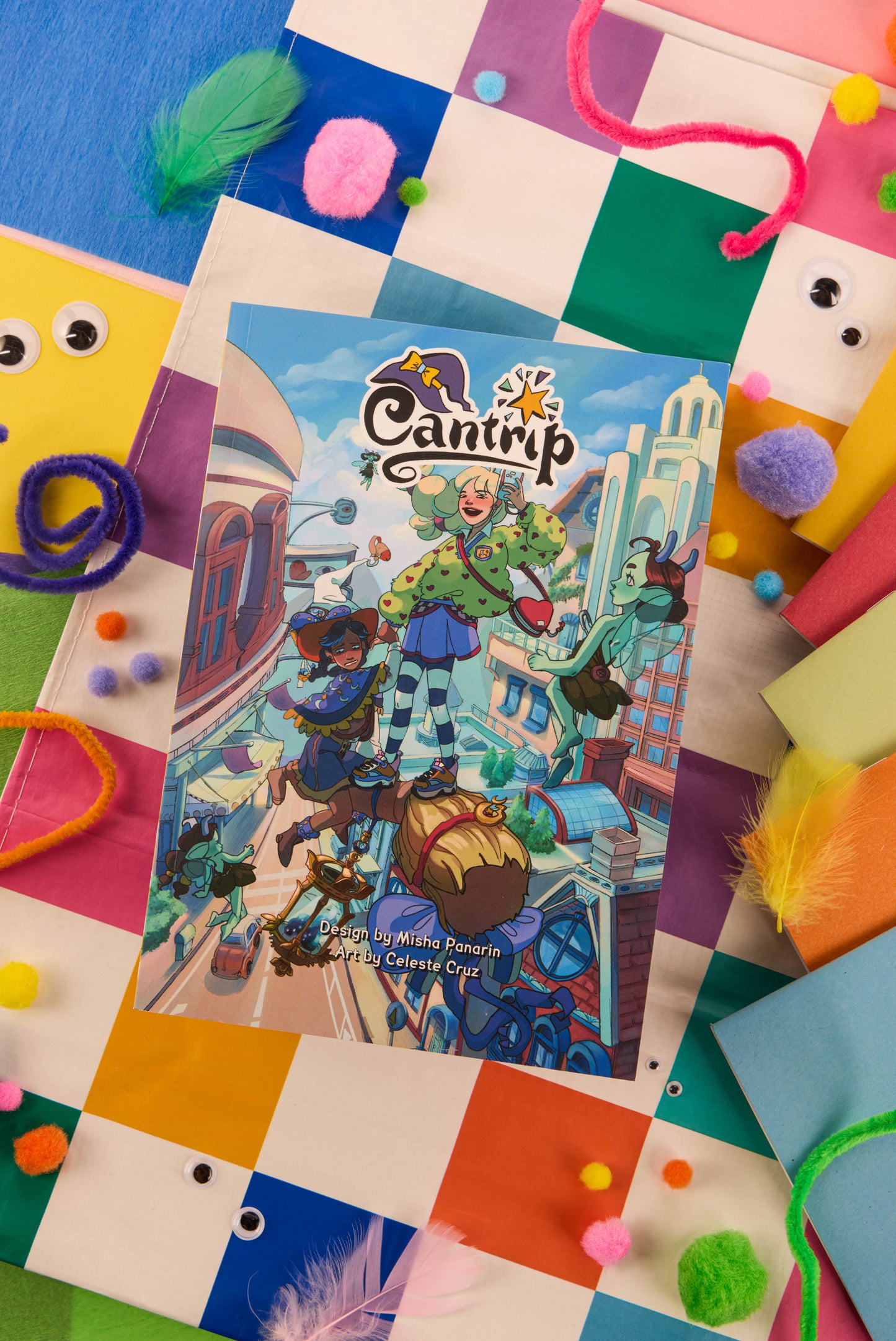 Product photography for Cantrip. The cover has an illustration of teenage witches. The book is placed upon a patchwork background